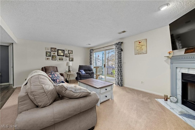 living area featuring visible vents, baseboards, a fireplace, a textured ceiling, and light colored carpet