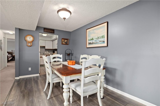 dining space with a textured ceiling, baseboards, and dark wood-style floors