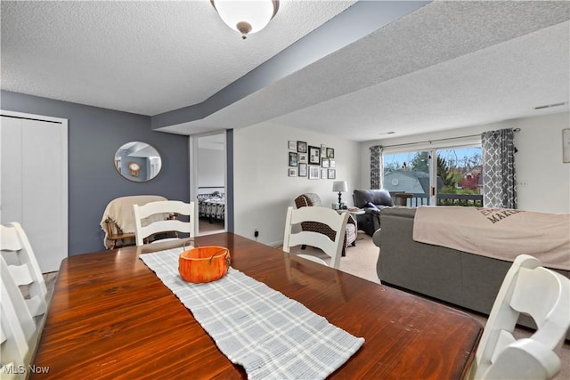 dining room with wood finished floors, a textured ceiling, and visible vents