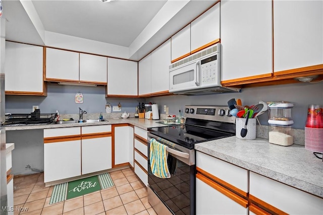 kitchen with electric range, a sink, white microwave, and light countertops