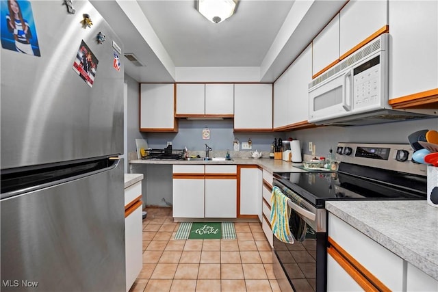 kitchen featuring light countertops, white cabinets, stainless steel appliances, and light tile patterned floors