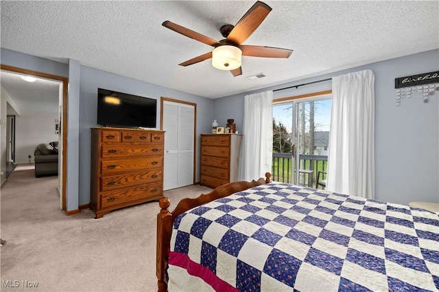 carpeted bedroom featuring a textured ceiling, access to exterior, visible vents, a closet, and ceiling fan