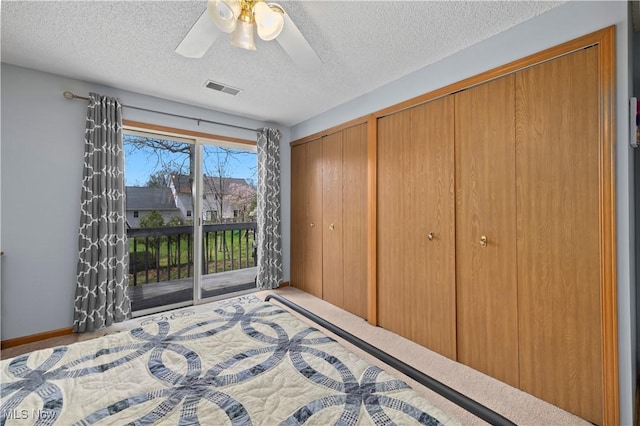 bedroom with a ceiling fan, a textured ceiling, multiple closets, access to outside, and visible vents