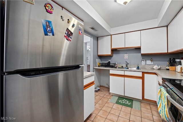 kitchen featuring light countertops, freestanding refrigerator, white cabinetry, and a sink