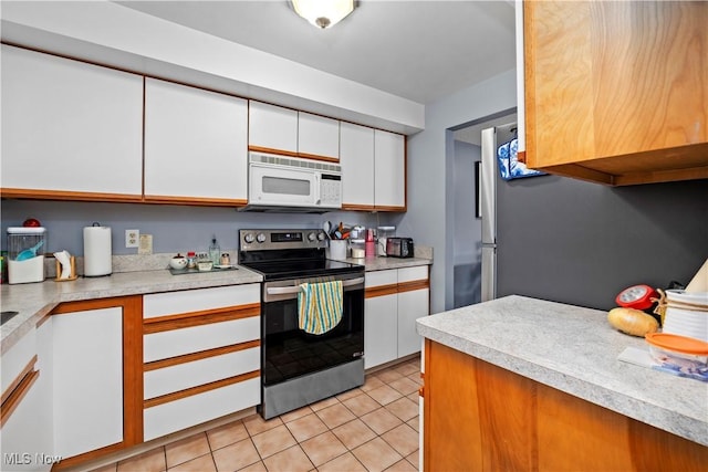 kitchen featuring light countertops, white microwave, white cabinetry, and stainless steel range with electric stovetop