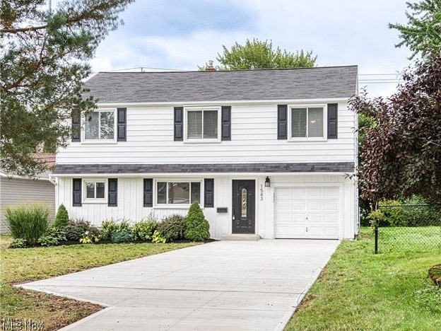 traditional-style home featuring fence, driveway, a front lawn, and a garage
