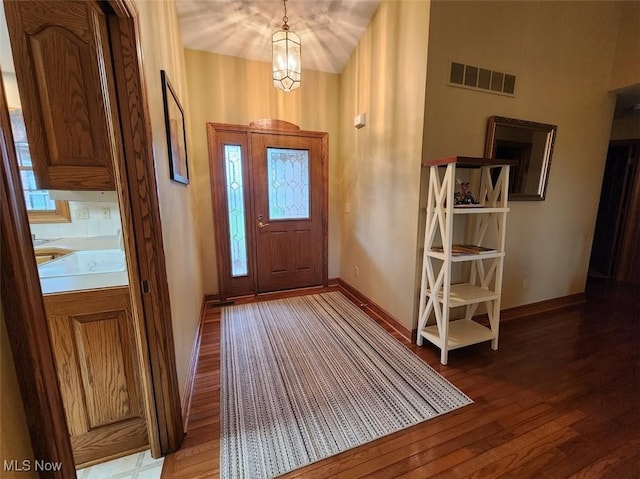 foyer entrance featuring baseboards, wood finished floors, visible vents, and plenty of natural light