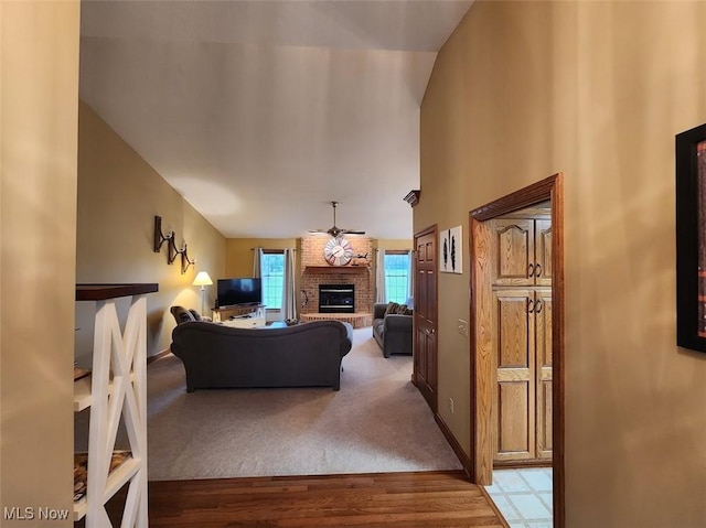 living room featuring high vaulted ceiling, a ceiling fan, wood finished floors, a fireplace, and baseboards