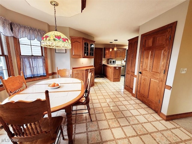 dining space featuring baseboards and light floors