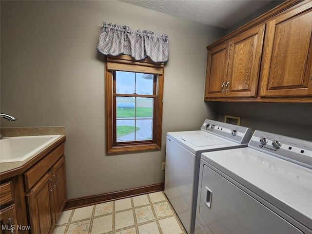 washroom featuring a sink, light floors, cabinet space, washing machine and dryer, and baseboards