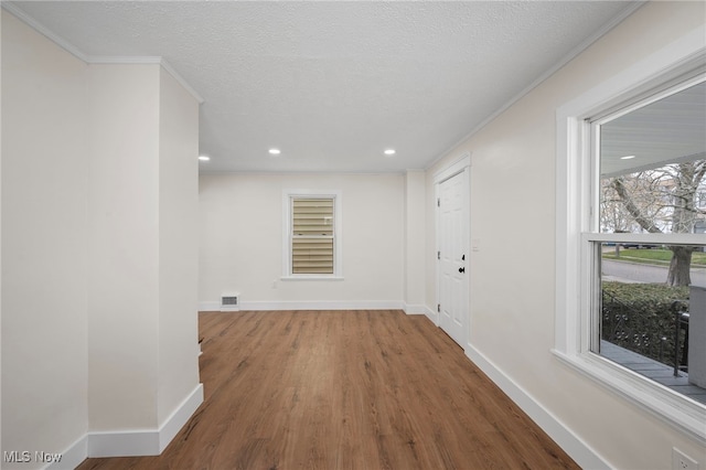 hallway with baseboards, visible vents, recessed lighting, wood finished floors, and ornamental molding