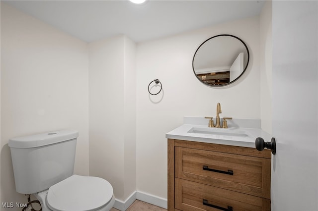half bathroom featuring baseboards, toilet, and vanity