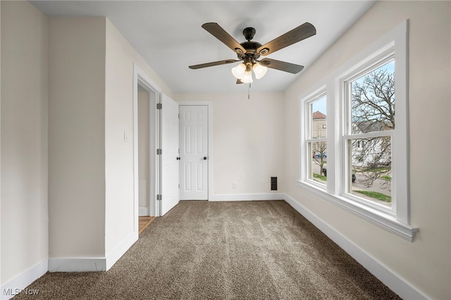 carpeted spare room featuring baseboards and a ceiling fan