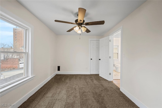 carpeted spare room featuring baseboards and ceiling fan