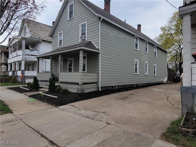 view of side of property with a chimney and a porch