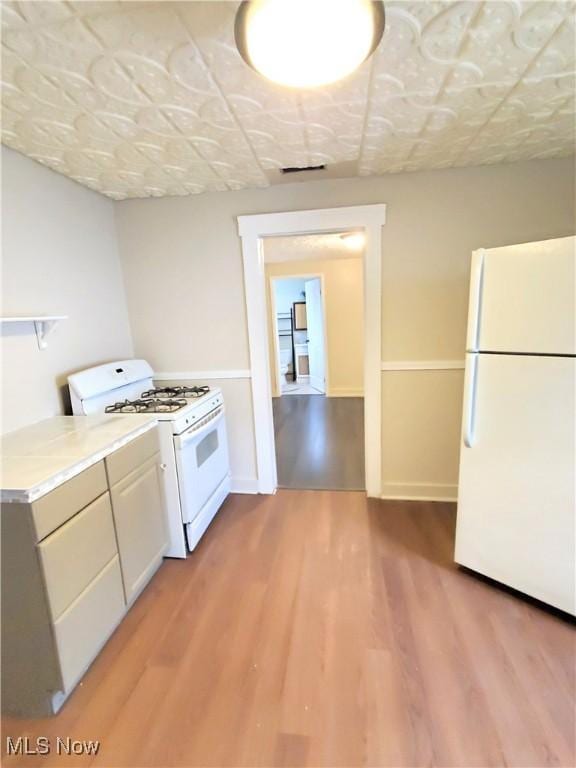 kitchen with open shelves, white appliances, light wood-style floors, and light countertops