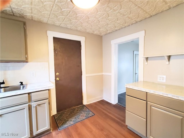 kitchen featuring decorative backsplash, open shelves, a sink, light countertops, and wood finished floors