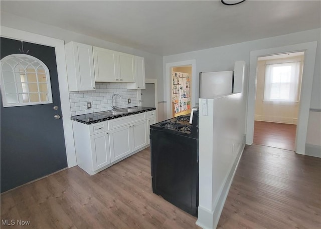 kitchen with dark countertops, light wood finished floors, white cabinetry, and a sink