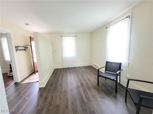 unfurnished room featuring dark wood-style floors, baseboards, and visible vents