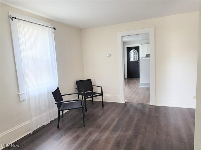 sitting room with baseboards and dark wood-style flooring