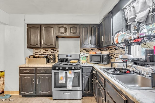 kitchen with light countertops, decorative backsplash, stainless steel appliances, and a sink