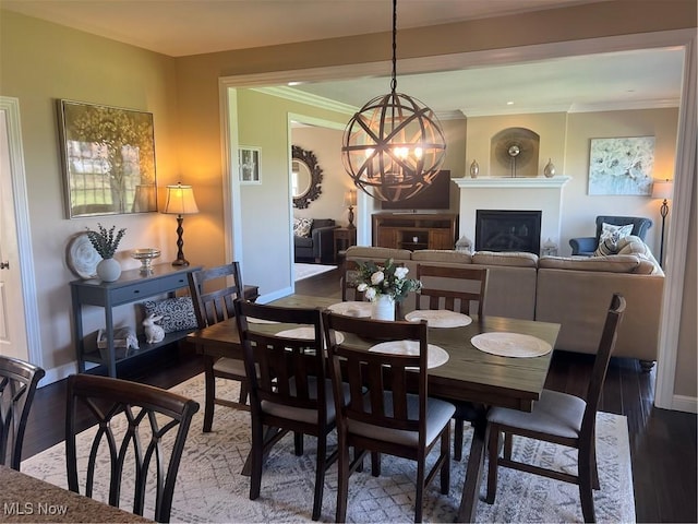 dining room with a chandelier, crown molding, a glass covered fireplace, and wood finished floors