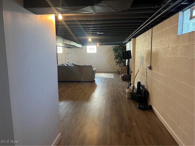 basement featuring concrete block wall, wood finished floors, and baseboards