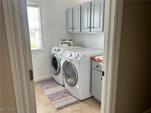 washroom featuring baseboards, light tile patterned flooring, independent washer and dryer, and cabinet space