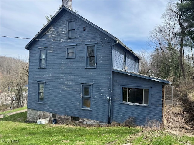 view of side of property featuring a chimney and a yard