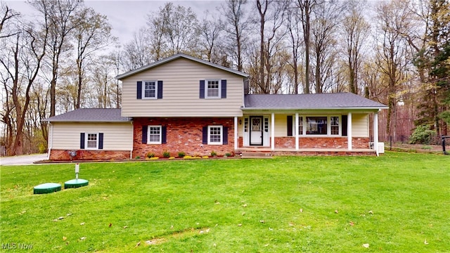 split level home featuring a front lawn, covered porch, and brick siding