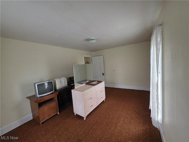 unfurnished office featuring dark colored carpet and baseboards