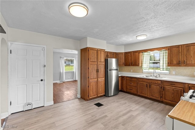 120 Hillcrest Dr, Wellsburg, WV 26070 - kitchen with a sink, visible vents, freestanding refrigerator, brown cabinetry, and light countertops