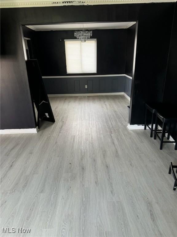 empty room featuring an inviting chandelier, wood finished floors, and baseboards