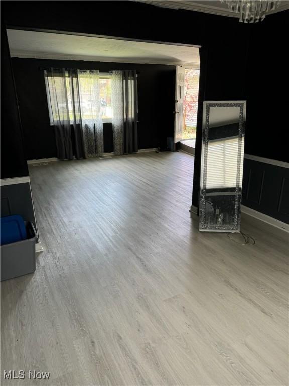 unfurnished living room with wood finished floors and an inviting chandelier