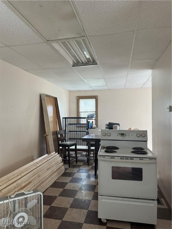 kitchen with dark floors, a drop ceiling, and white electric range