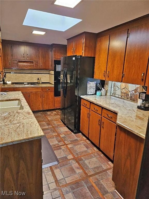 kitchen with black appliances, a skylight, and tasteful backsplash