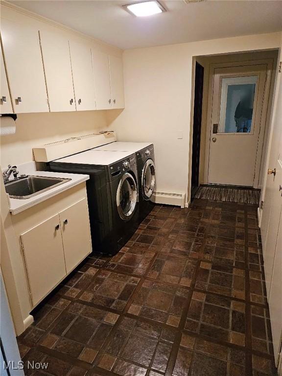 washroom featuring a sink, baseboards, separate washer and dryer, cabinet space, and brick patterned floor