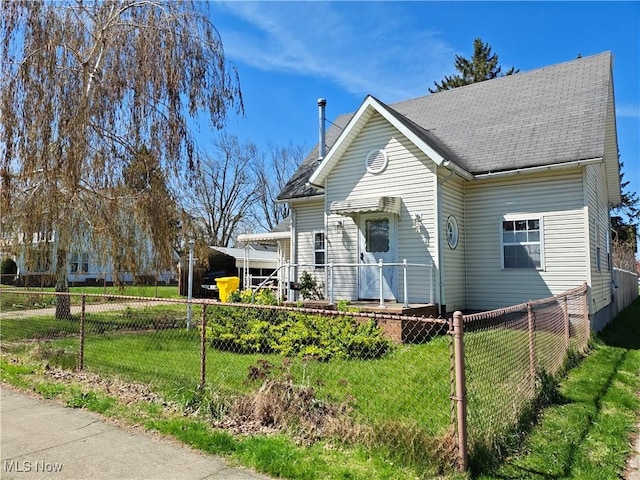 view of front of home with a front lawn, roof with shingles, and fence private yard