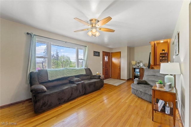 living area featuring light wood-style floors, a ceiling fan, and baseboards