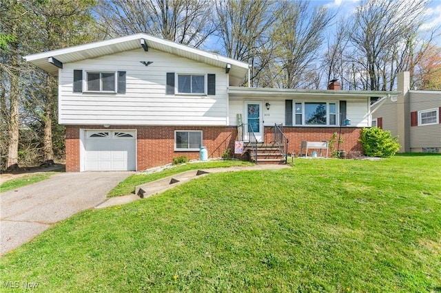 split level home with a garage, a chimney, aphalt driveway, a front yard, and brick siding