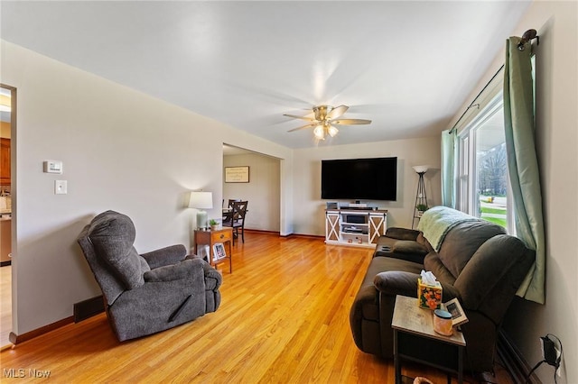 living room with ceiling fan, baseboards, and light wood-style flooring