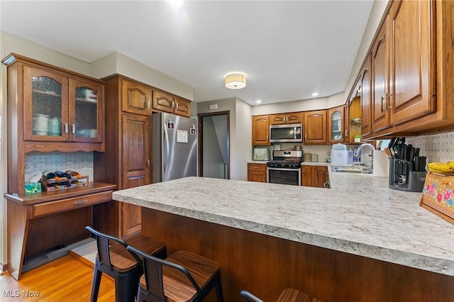kitchen featuring a peninsula, appliances with stainless steel finishes, a sink, and light countertops