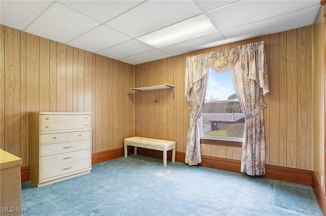 interior space featuring wood walls, carpet flooring, and a drop ceiling