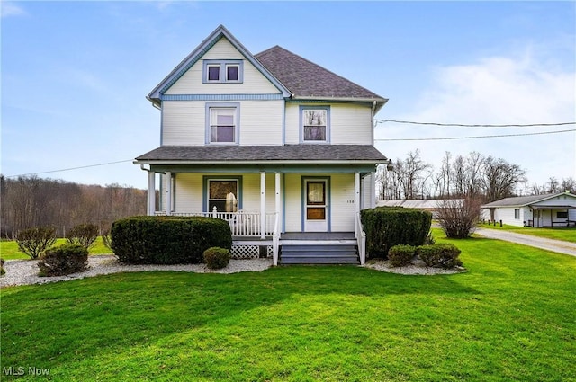 victorian-style house featuring a porch, a shingled roof, and a front yard