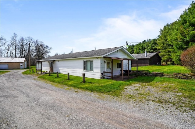 view of front facade featuring driveway, a front lawn, covered porch, and a detached garage