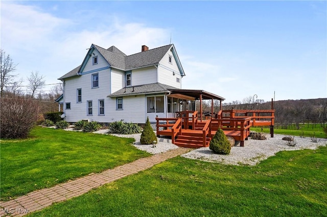 back of property featuring a wooden deck, a lawn, a chimney, and roof with shingles