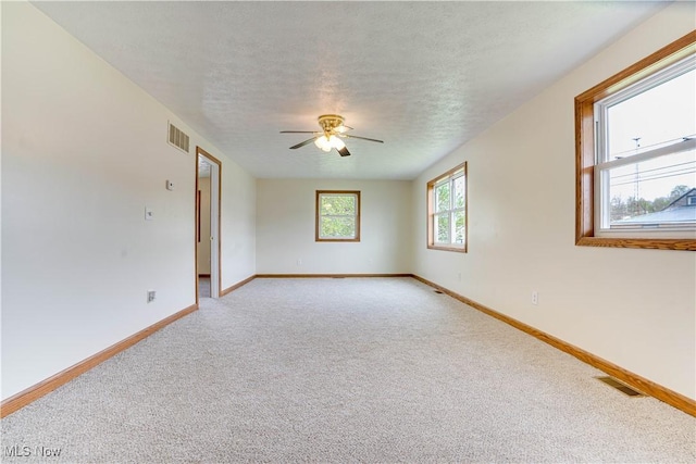 unfurnished room with baseboards, visible vents, light colored carpet, and ceiling fan