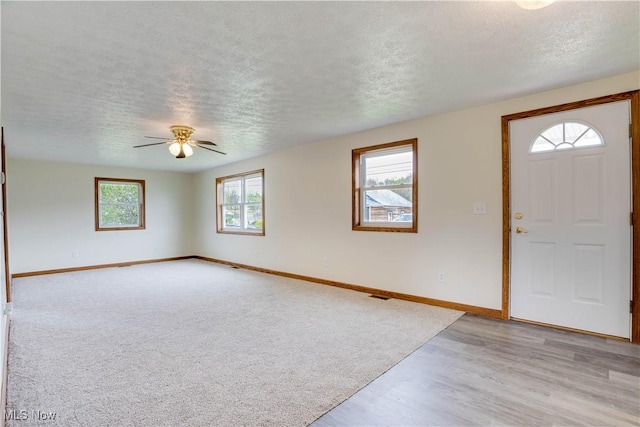 entrance foyer with light wood finished floors, a textured ceiling, a ceiling fan, and baseboards