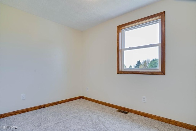 carpeted spare room featuring baseboards and visible vents