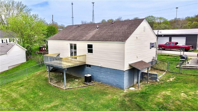 back of property with a detached garage, a lawn, a shingled roof, and a fenced backyard